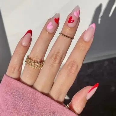 Nude almond nails with red hearts and a red French tip